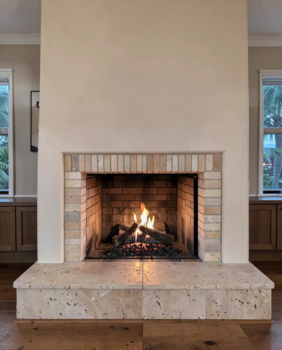 A masonry fireplace with a firebrick firebox and limestone hearth, a fire burning low (illustrative, generated).
